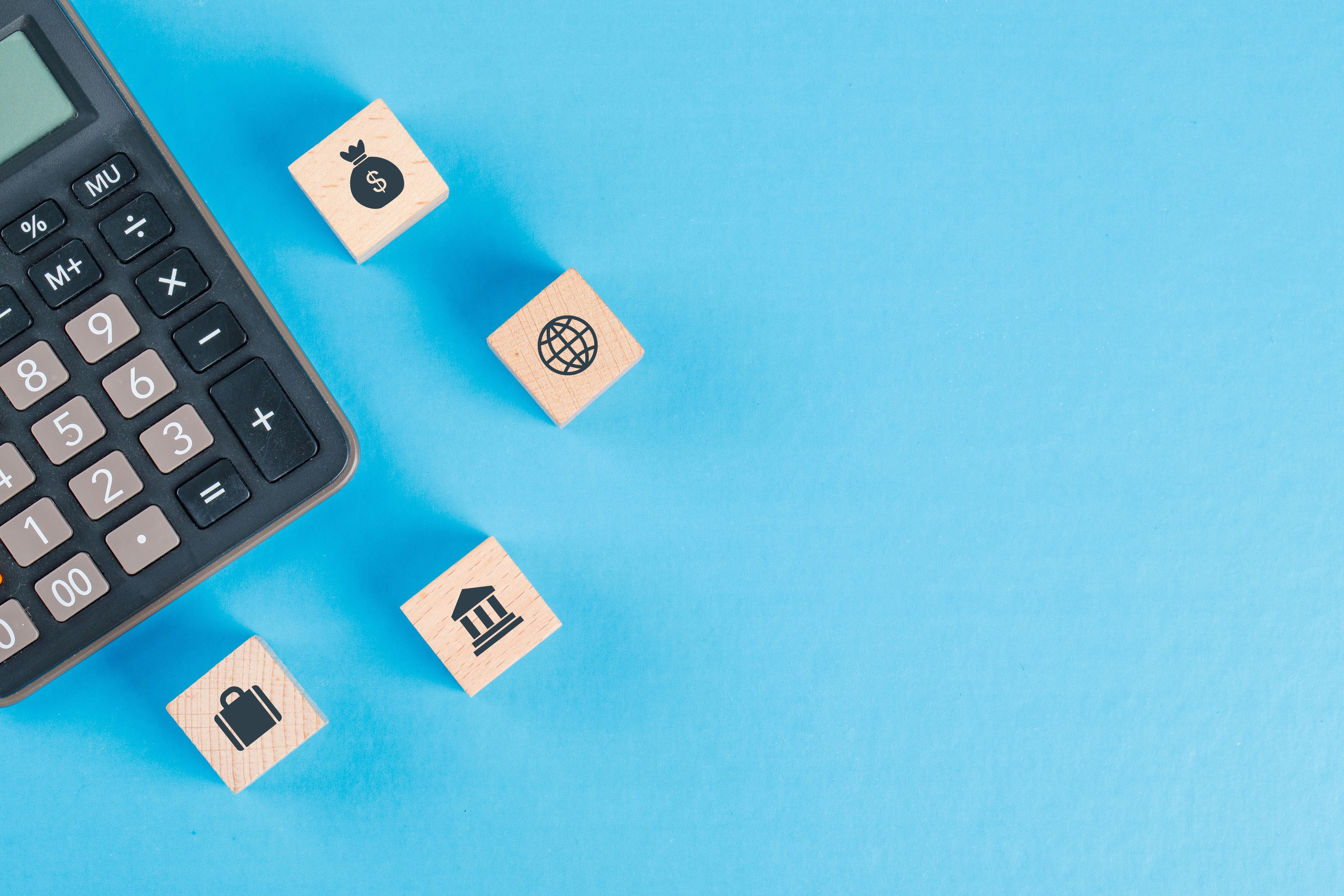 financial-concept-with-icons-wooden-cubes-calculator-blue-table-flat-lay